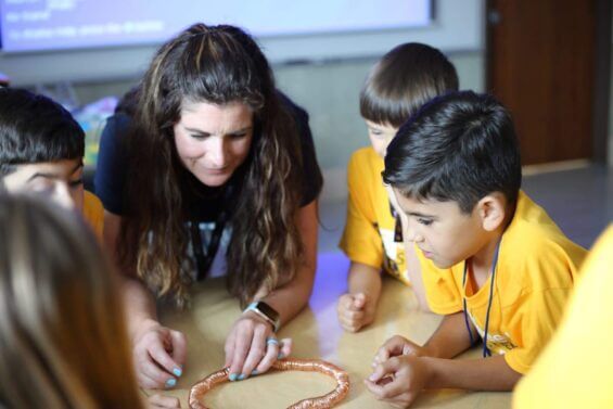 A woman leads an activity with young children in a classroom.