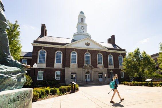 A student walks across a college campus.
