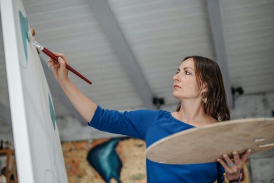 A woman paints on a canvas.