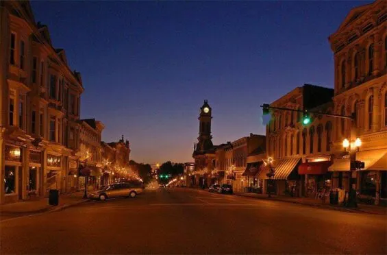 A street in Scott County is lit up by warm yellow streetlights as night falls.
